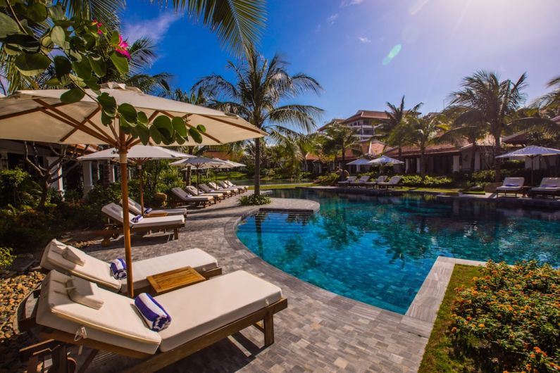 Family Hotel - white and brown lounge chairs beside swimming pool during daytime