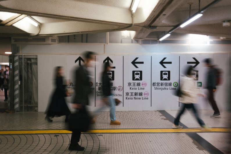 Train Routes - a group of people walking past a subway station