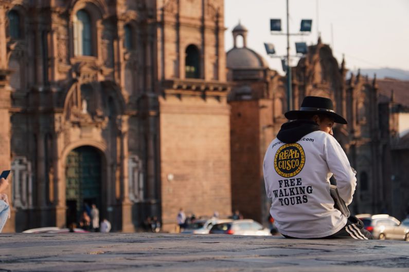 Walking Tours - a man in a white shirt and hat walking in front of a building