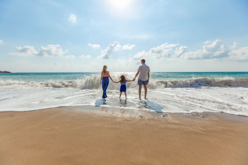 Family Travel - man, woman and child holding hands on seashore