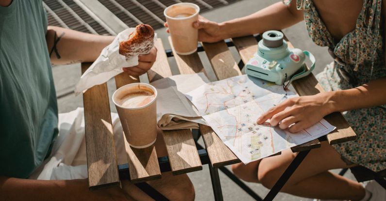 Coffee Tour - From above of crop anonymous couple searching route in map while having coffee and croissant