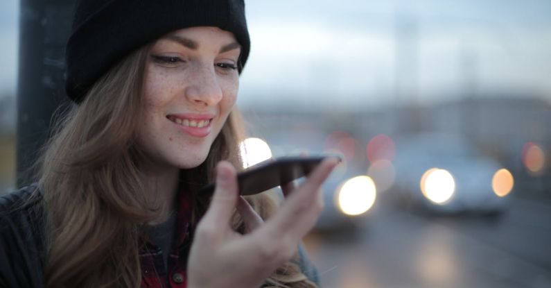 Travel Apps - Joyful young woman phoning on street in evening